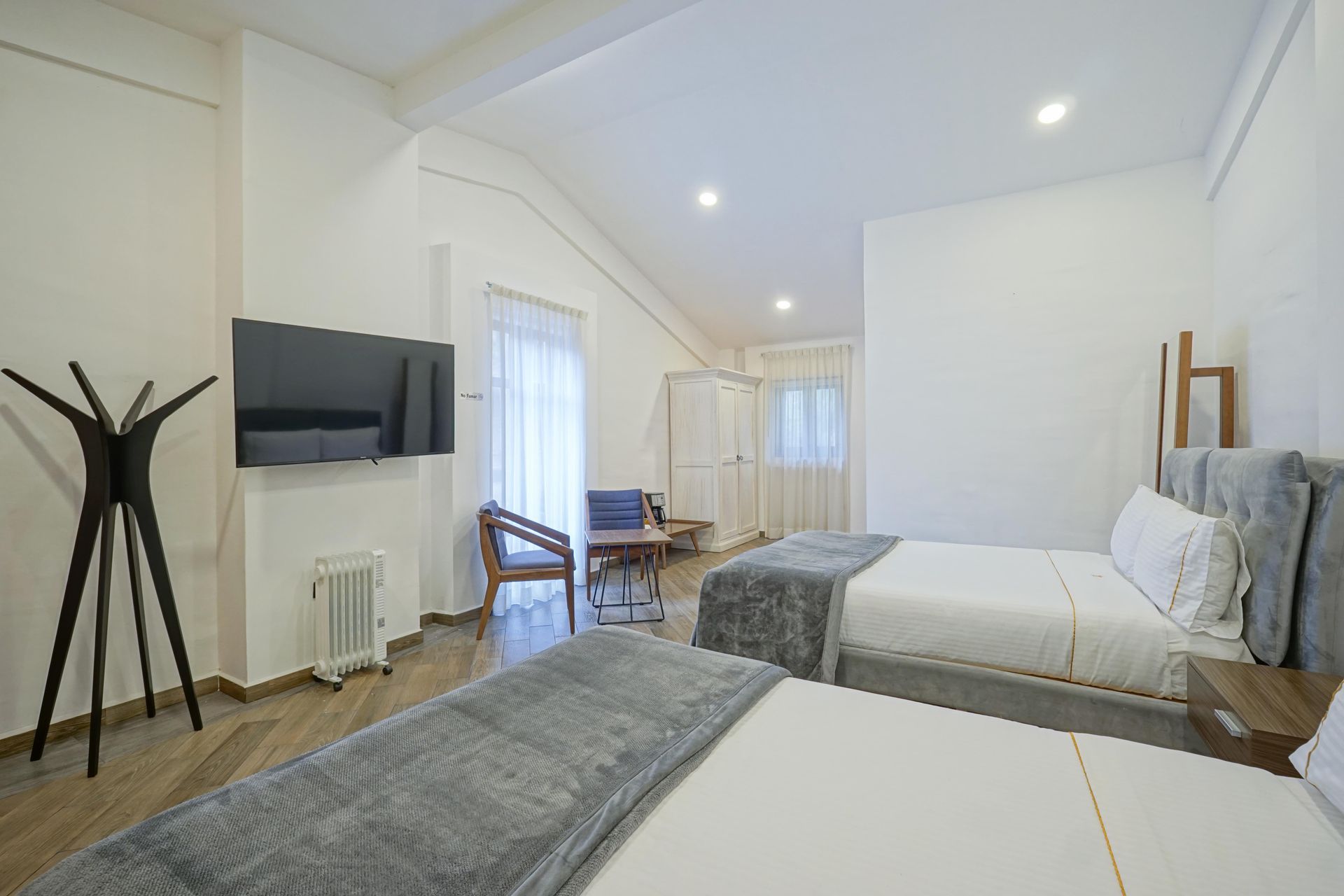 Bedroom with a bed, white wardrobe, coat rack, and red door.