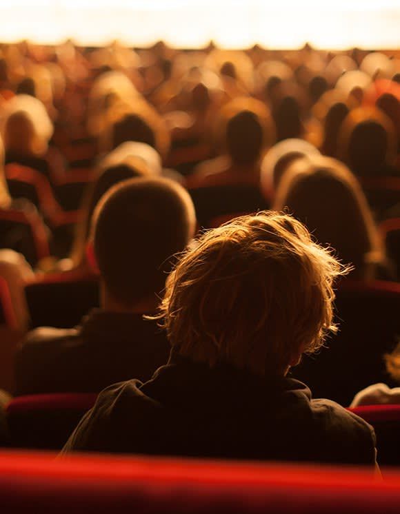 A group of people are sitting in a theater watching a show.