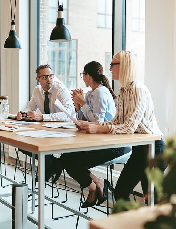 A group of people are sitting at a table having a meeting.