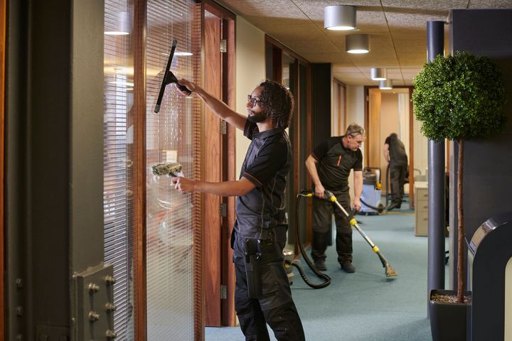 A man is cleaning a window with a squeegee in an office.