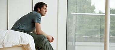 Young man sitting on edge of bed — Counseling Services in Teaneck, NJ