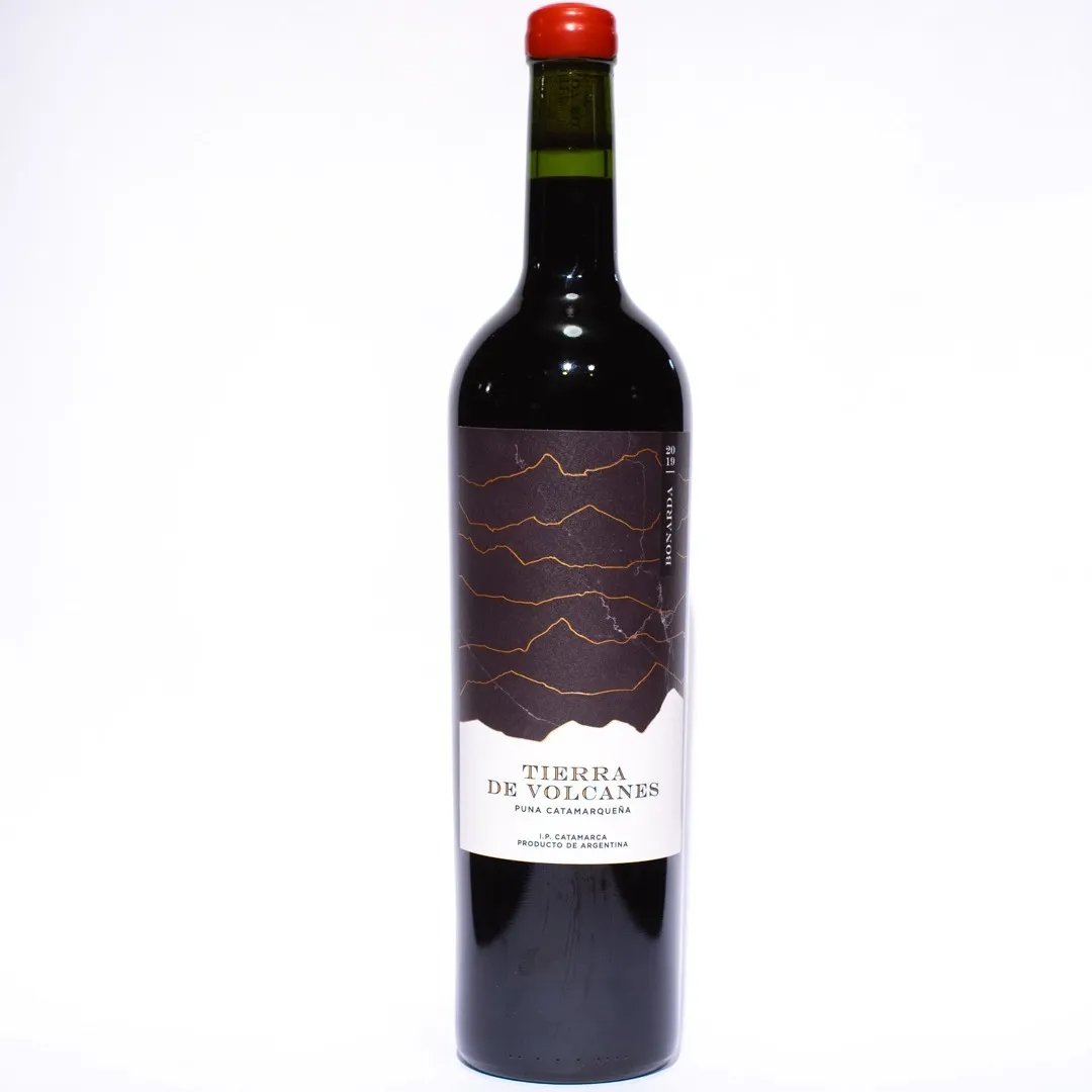 Botella de vino tinto Tierra de Volcanes con tapón rojo y etiqueta oscura.