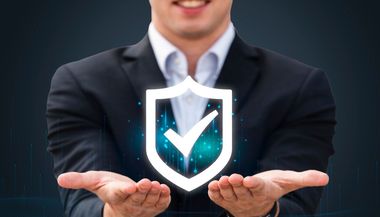 A man in a suit is holding a shield with a check mark on it.