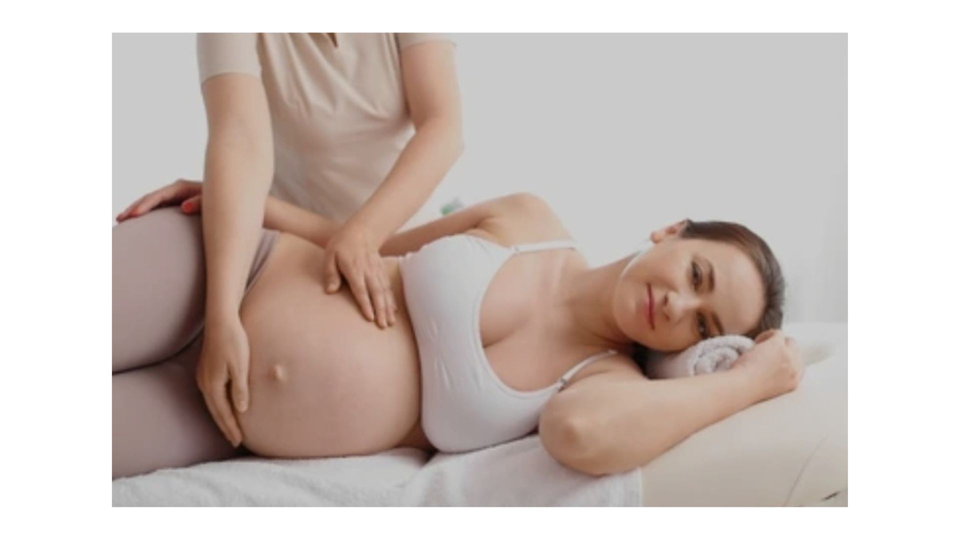 Mujer embarazada recibiendo masaje en una cama.