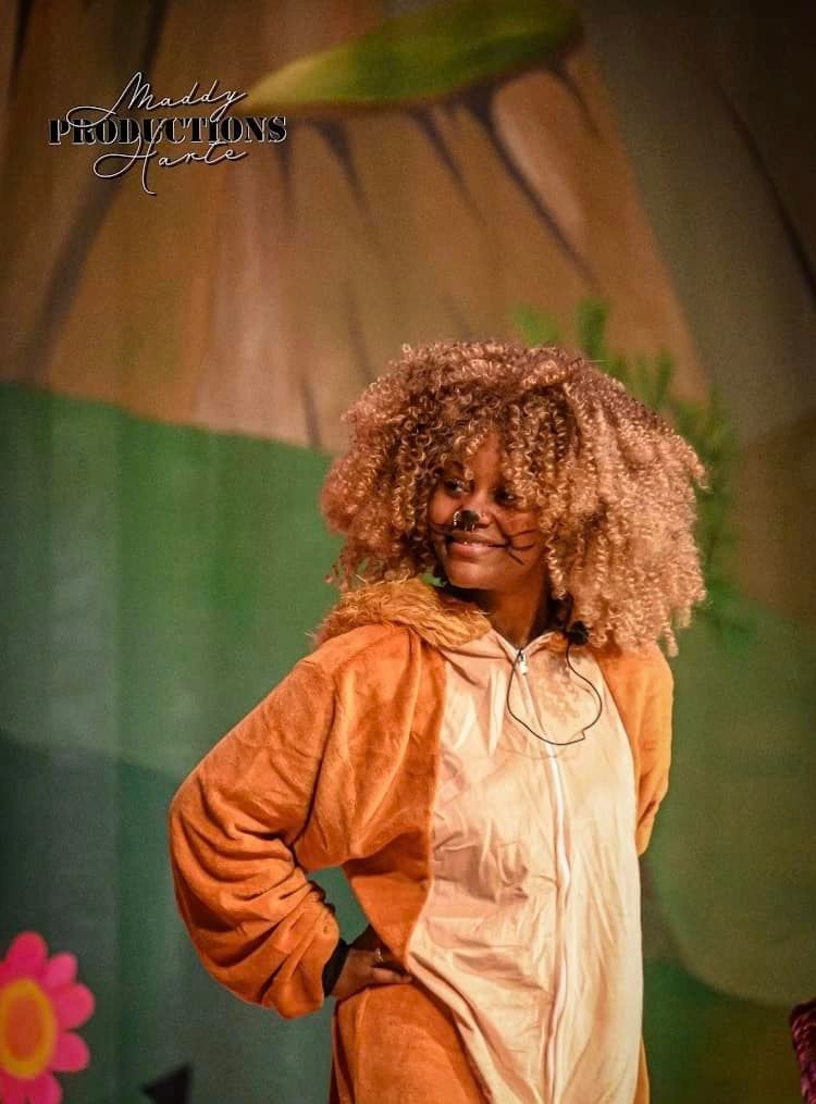 A woman in a lion costume is standing on a stage.