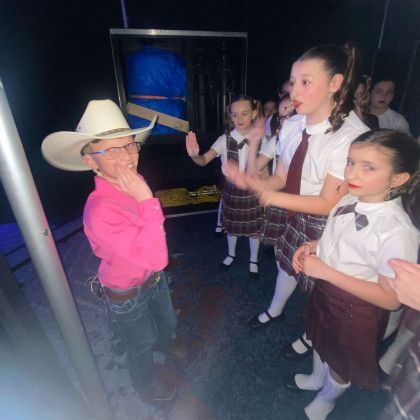 A man in a cowboy hat is talking to a group of children