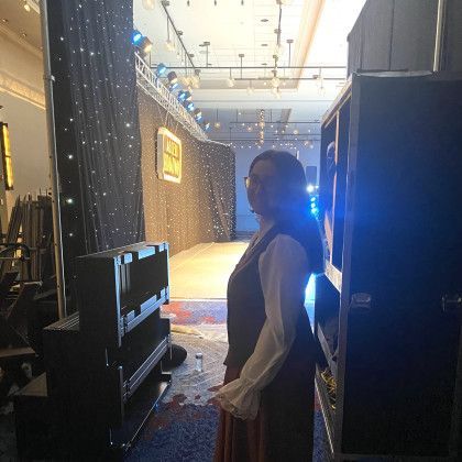 A woman is standing in front of a stage in a dark room.