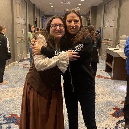 Two women are hugging each other in a hallway.