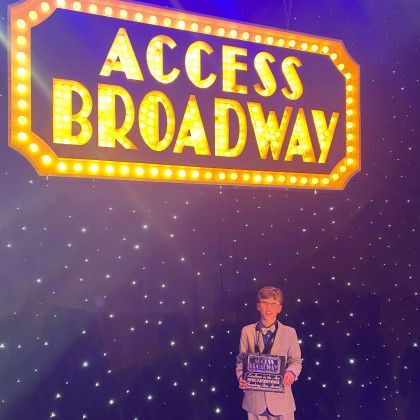 A boy is standing in front of a sign that says access broadway