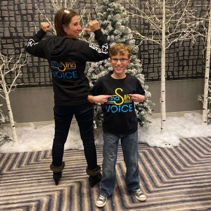 A woman and a boy are standing next to each other in front of a christmas tree.