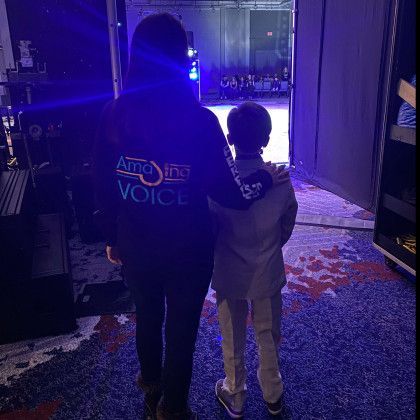 A man and a boy are standing next to each other in a dark room.