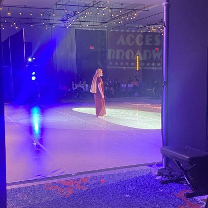 A woman is standing on a stage in a dark room with blue lights.