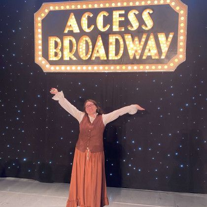 A woman is standing in front of a sign that says access broadway