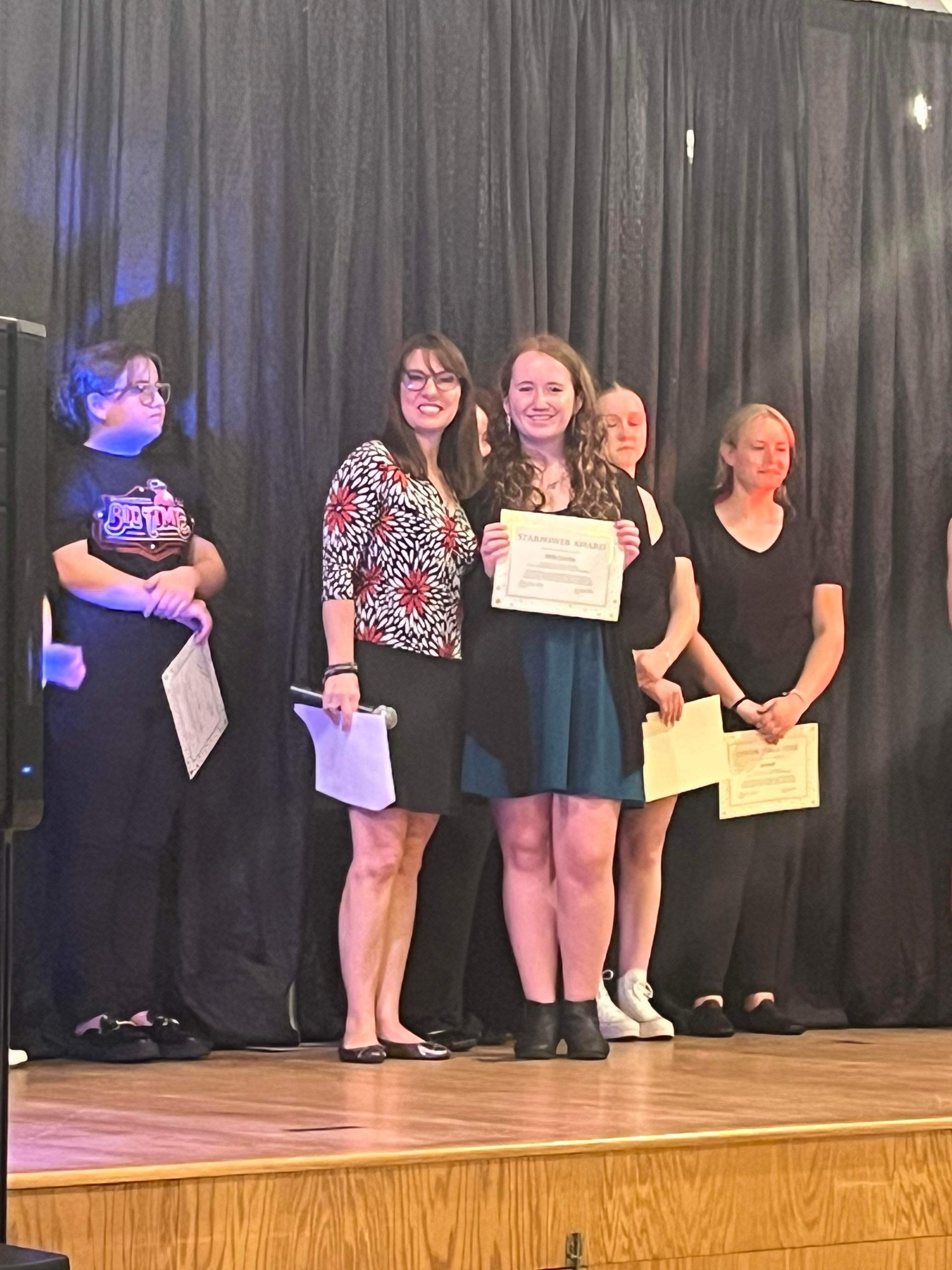 A group of women are standing on a stage holding certificates.