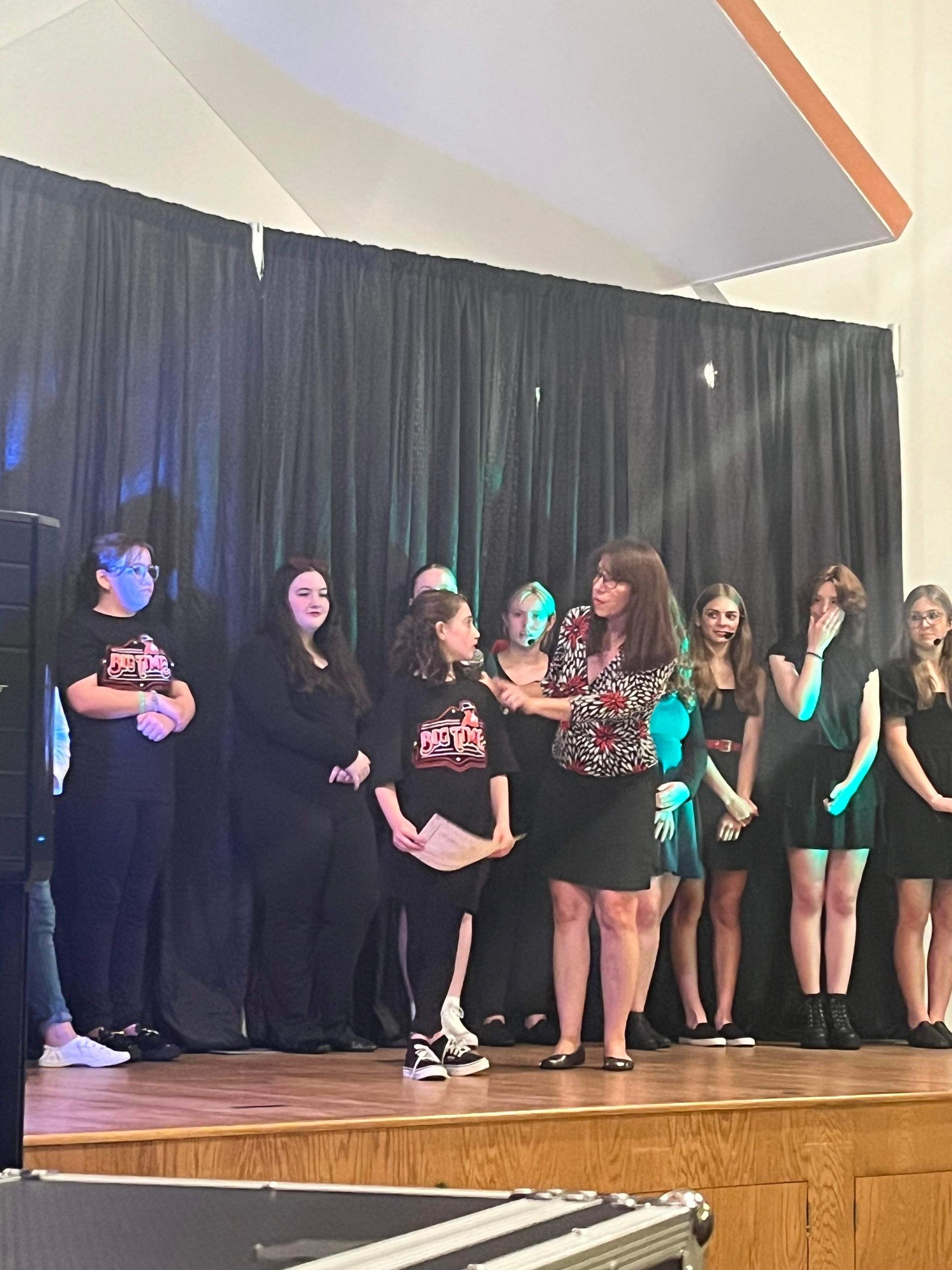A group of people are standing on a stage in front of a black curtain.