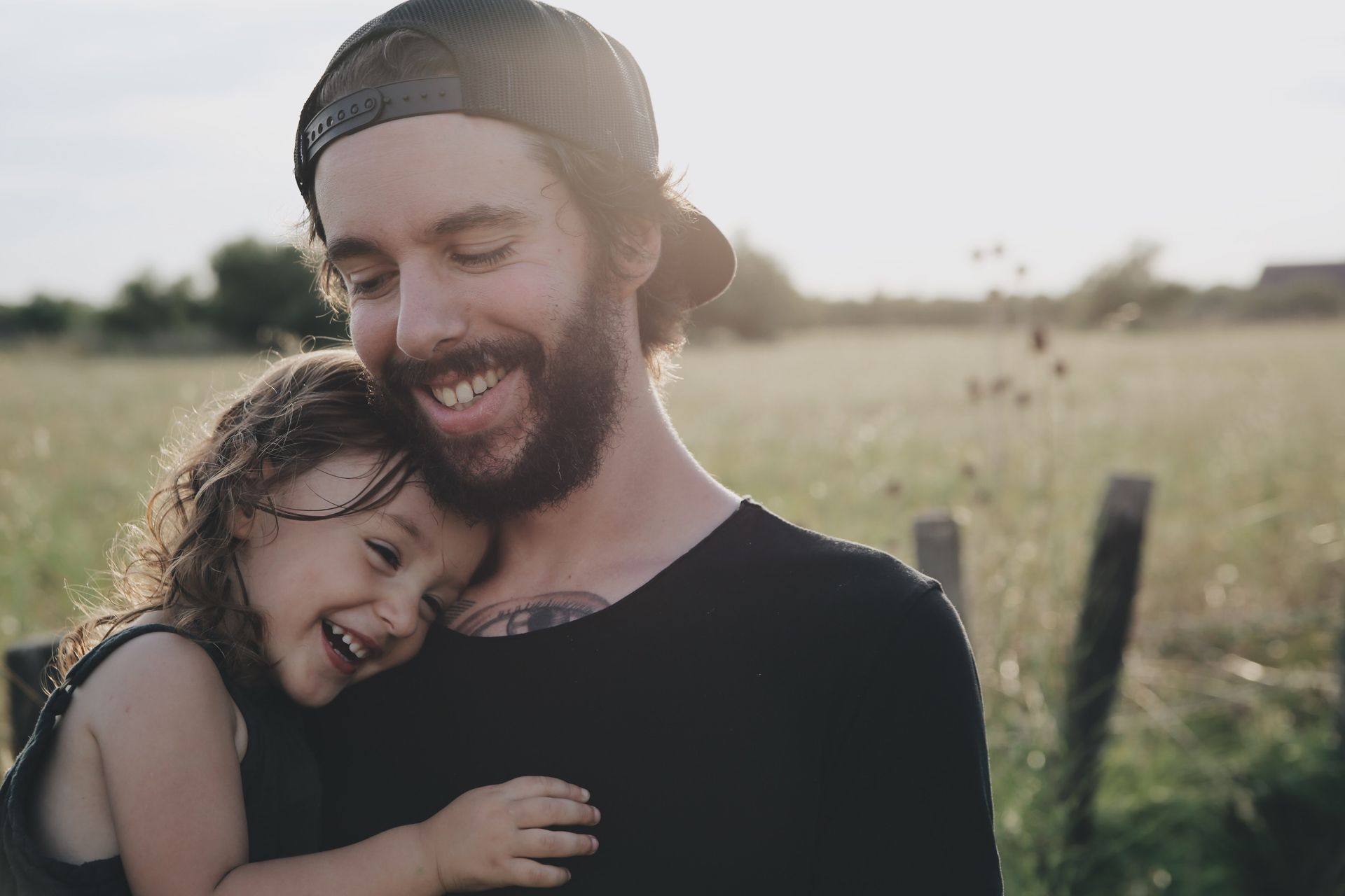 A man with a beard is holding a little girl in his arms.