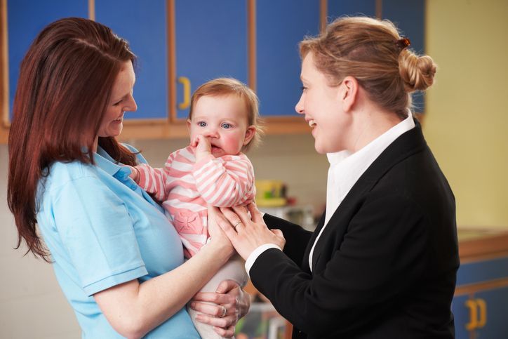 A woman is holding a baby and talking to another woman