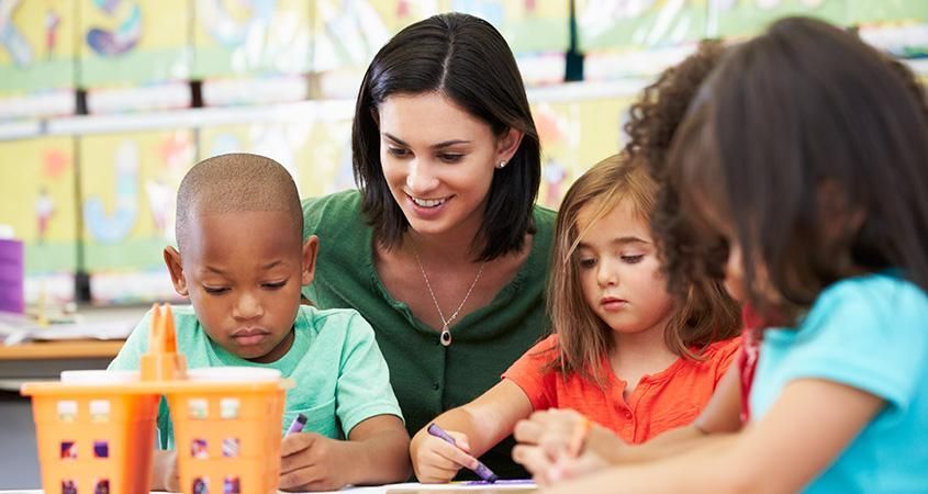 A teacher is teaching a group of children in a classroom.