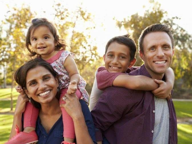 A family is posing for a picture in a park.