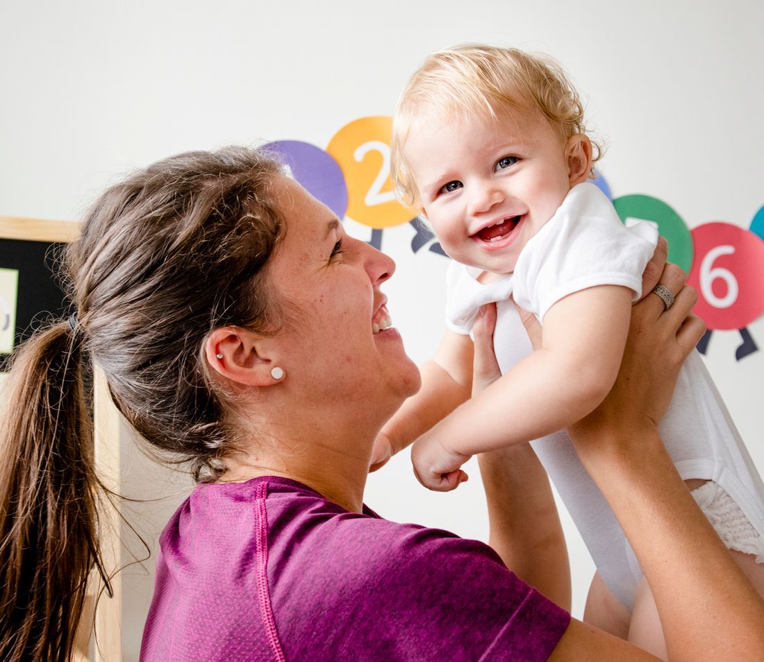 A woman in a purple shirt is holding a baby in her arms