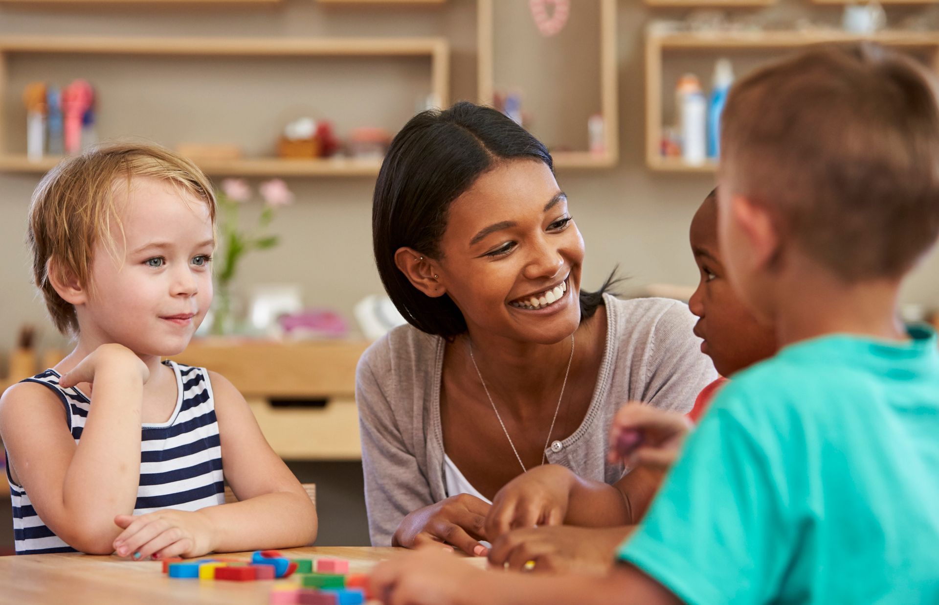 A woman is sitting at a table with a group of children.