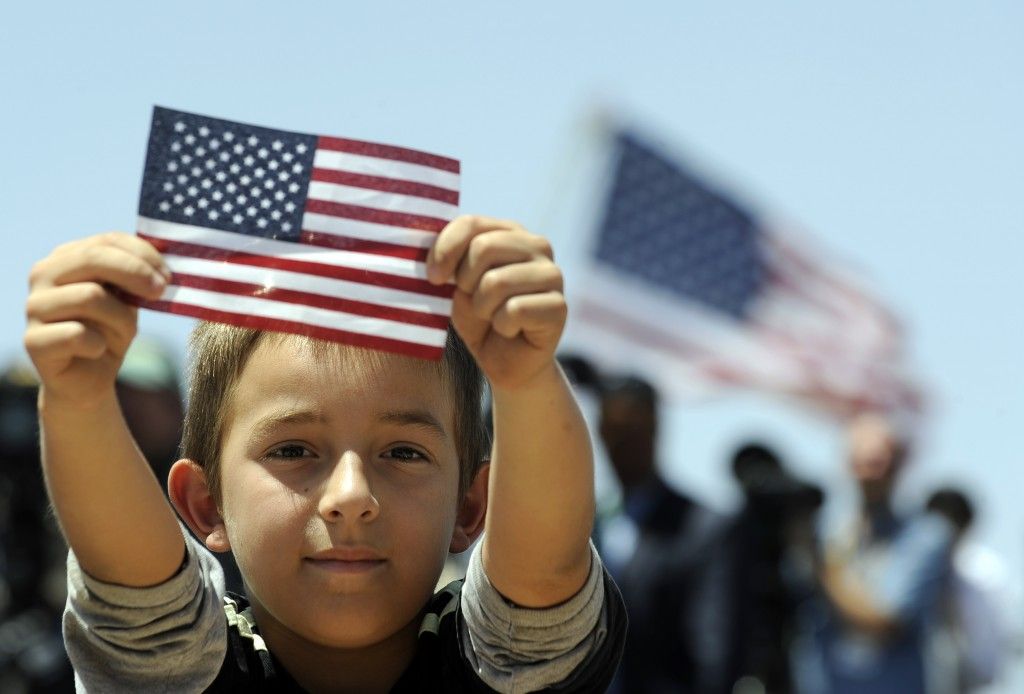 A young boy is holding an american flag in his hands