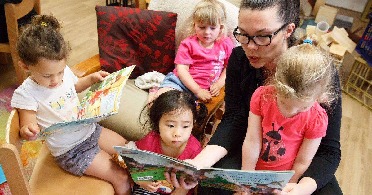 A woman is reading a book to a group of young girls.