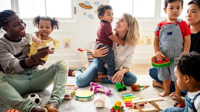 A group of people are sitting on the floor playing with toys.