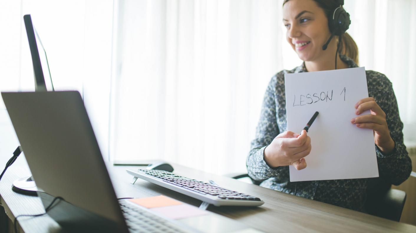 A woman is holding a piece of paper in front of a laptop computer.