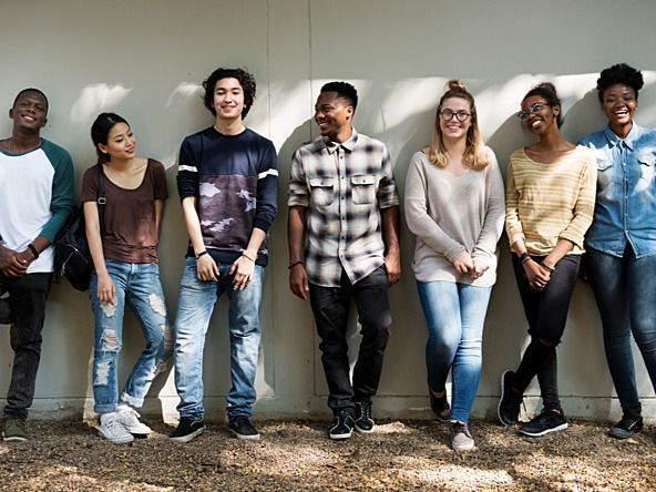 A group of young people are standing next to each other in front of a wall.