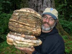 A man is holding a large mushroom in his hands.