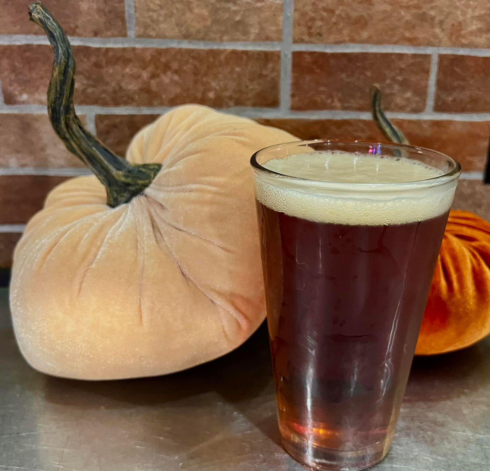 A glass of beer next to a pumpkin on a table