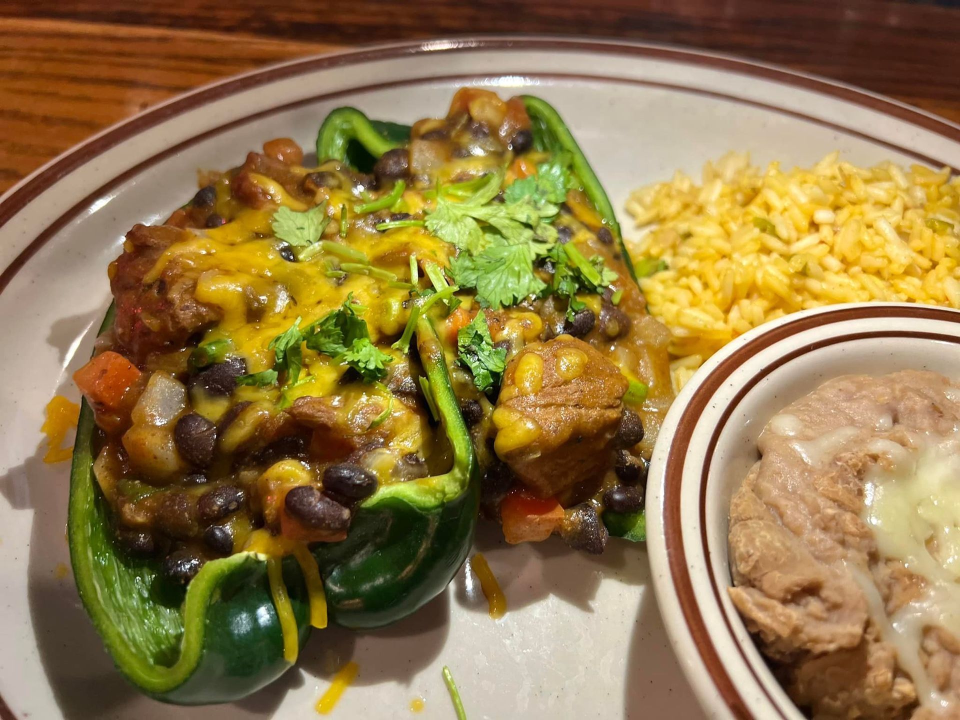 A plate of stuffed peppers with rice and beans on a table.