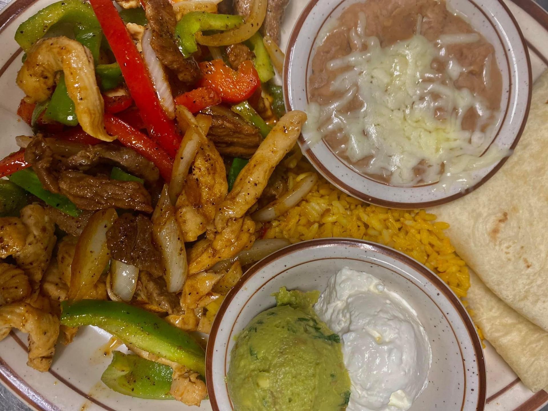 A plate of food with rice beans guacamole and sour cream