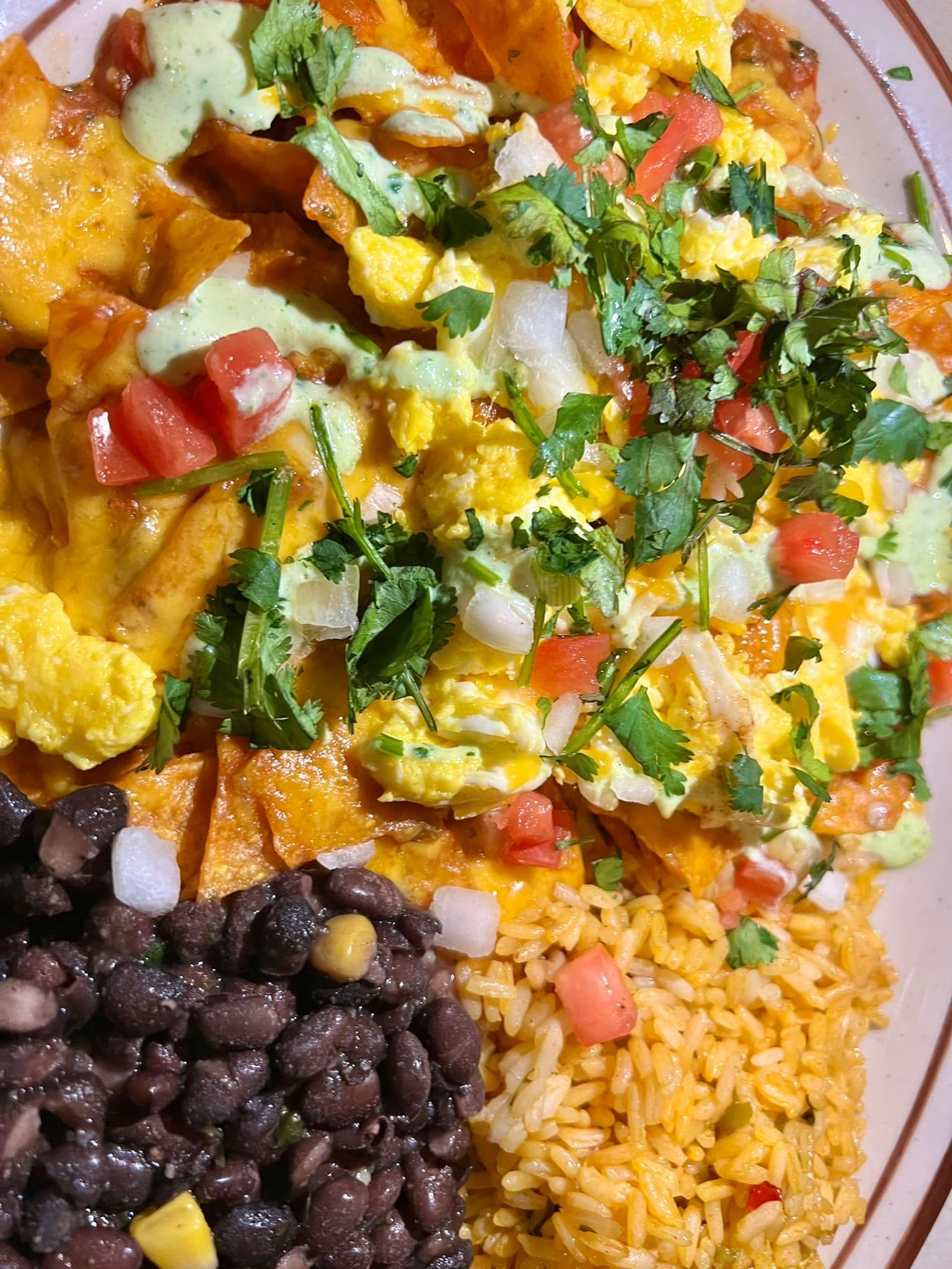 A plate of food with rice , beans and nachos on a table.