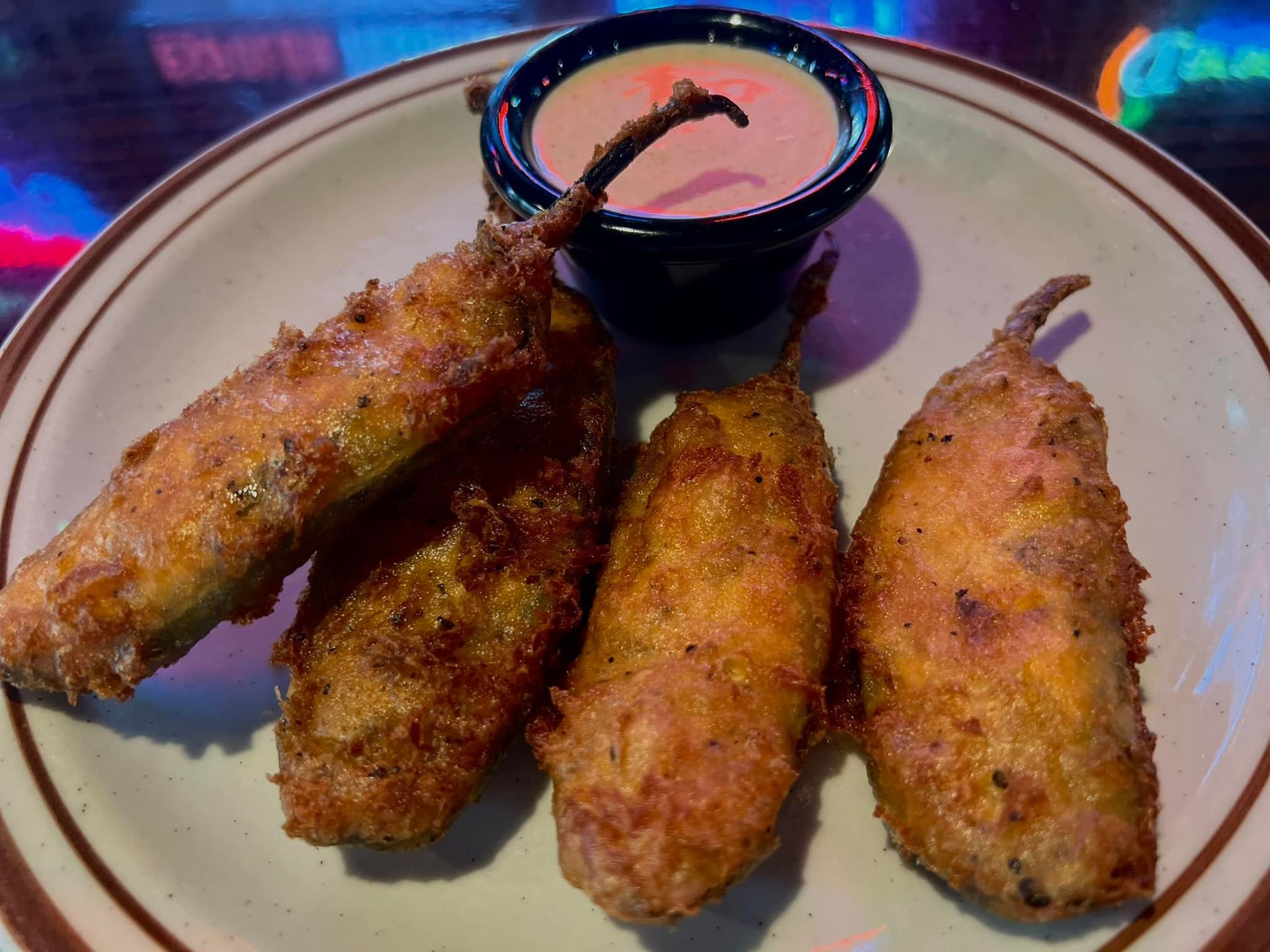 A plate of fried jalapenos with a dipping sauce