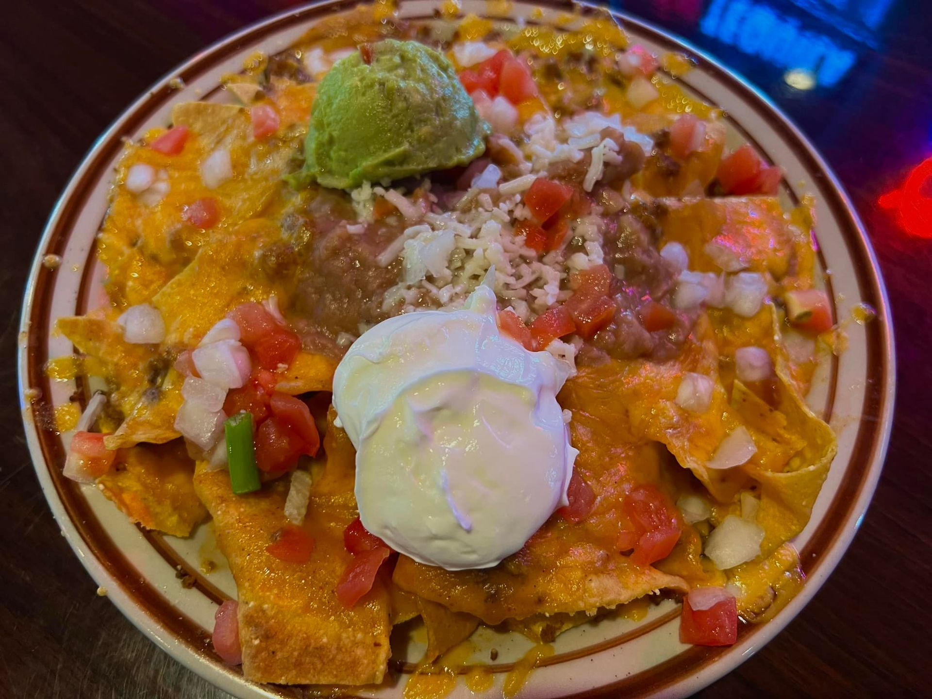 A plate of nachos with guacamole and sour cream on a table.