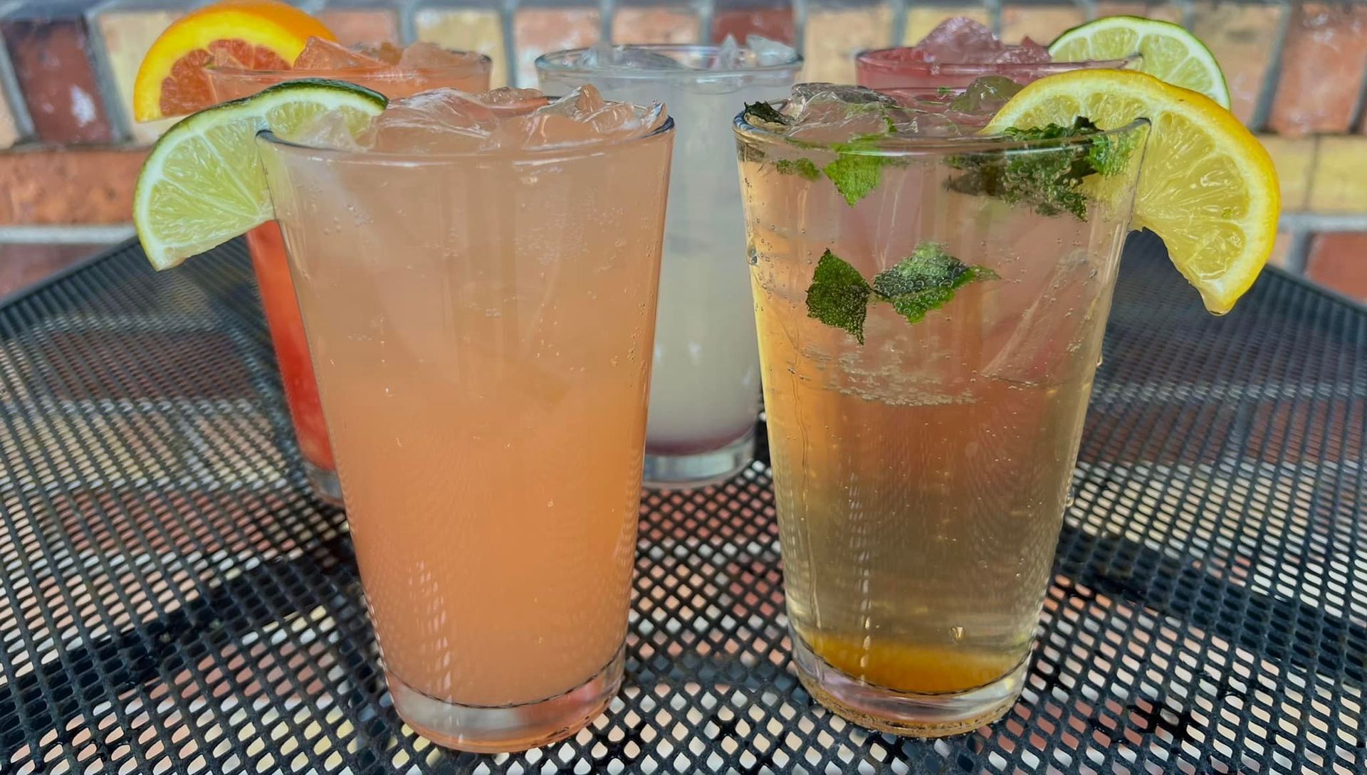 Two glasses of drinks with lemon slices on a table.
