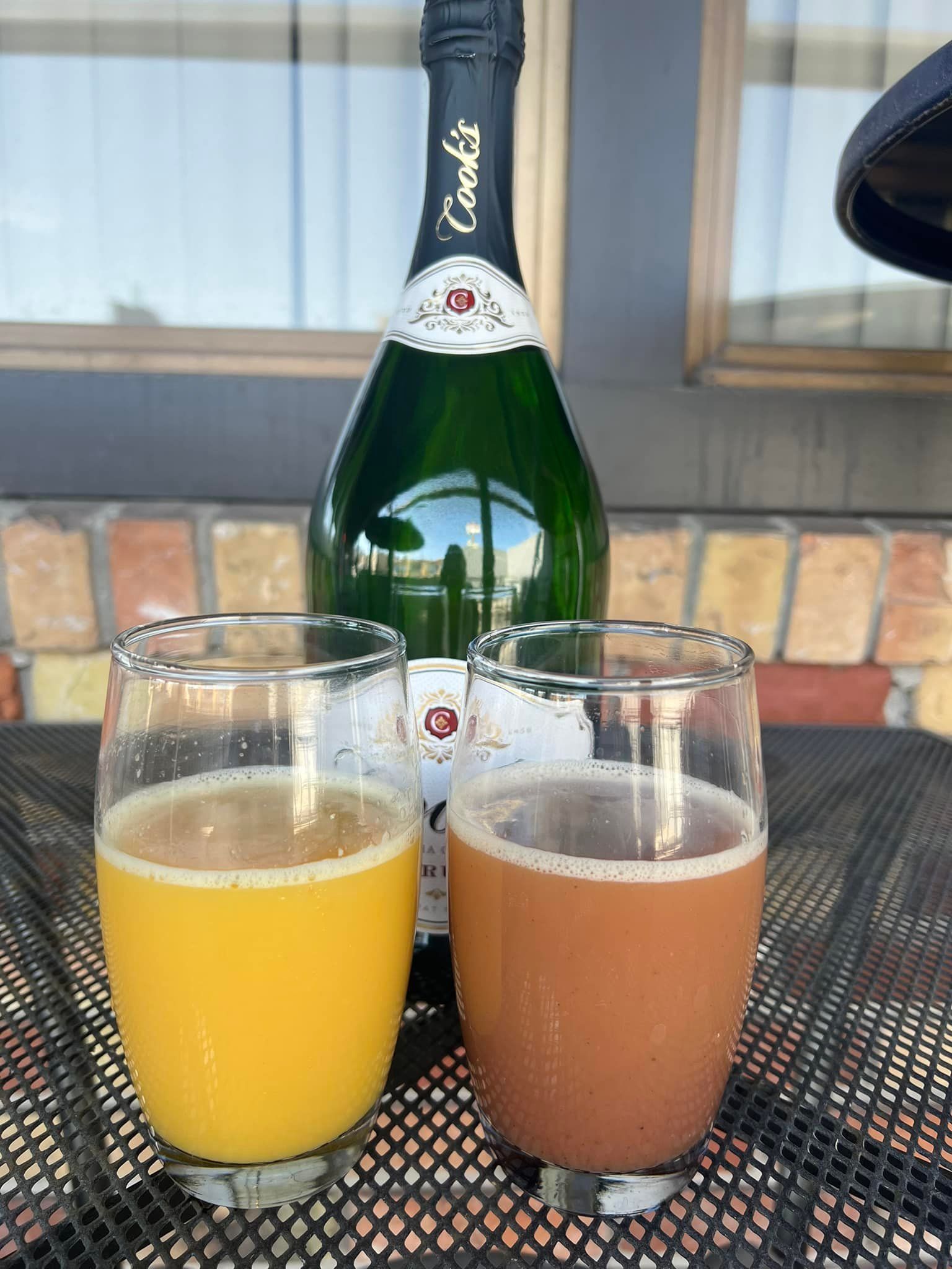 Two glasses of beverages next to a bottle of cava