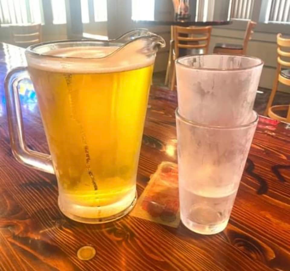 A pitcher of beer and two glasses of water on a wooden table.