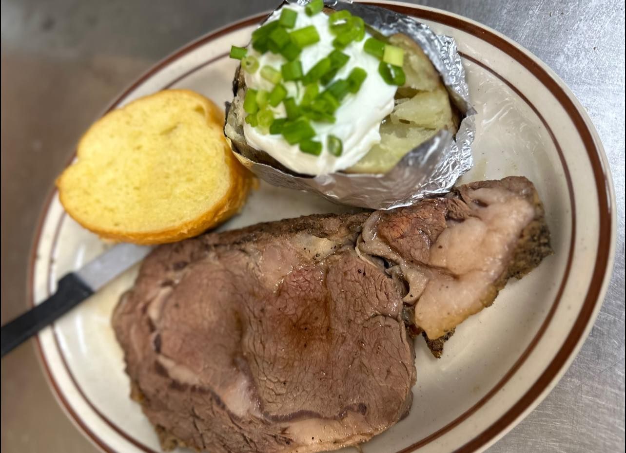 A plate of food with a steak and a baked potato on a table.
