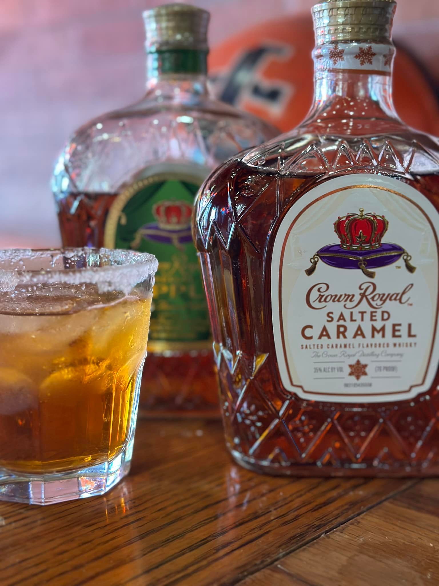 A bottle of crown royal salted caramel whiskey next to a glass of whiskey