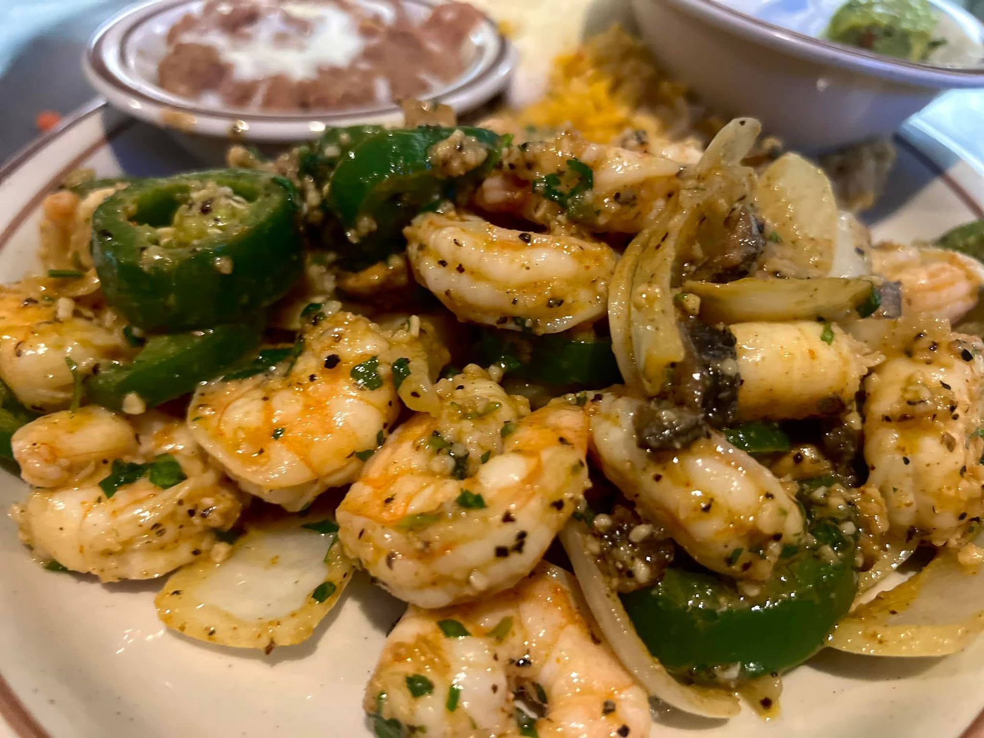 A close up of a plate of shrimp and peppers on a table.