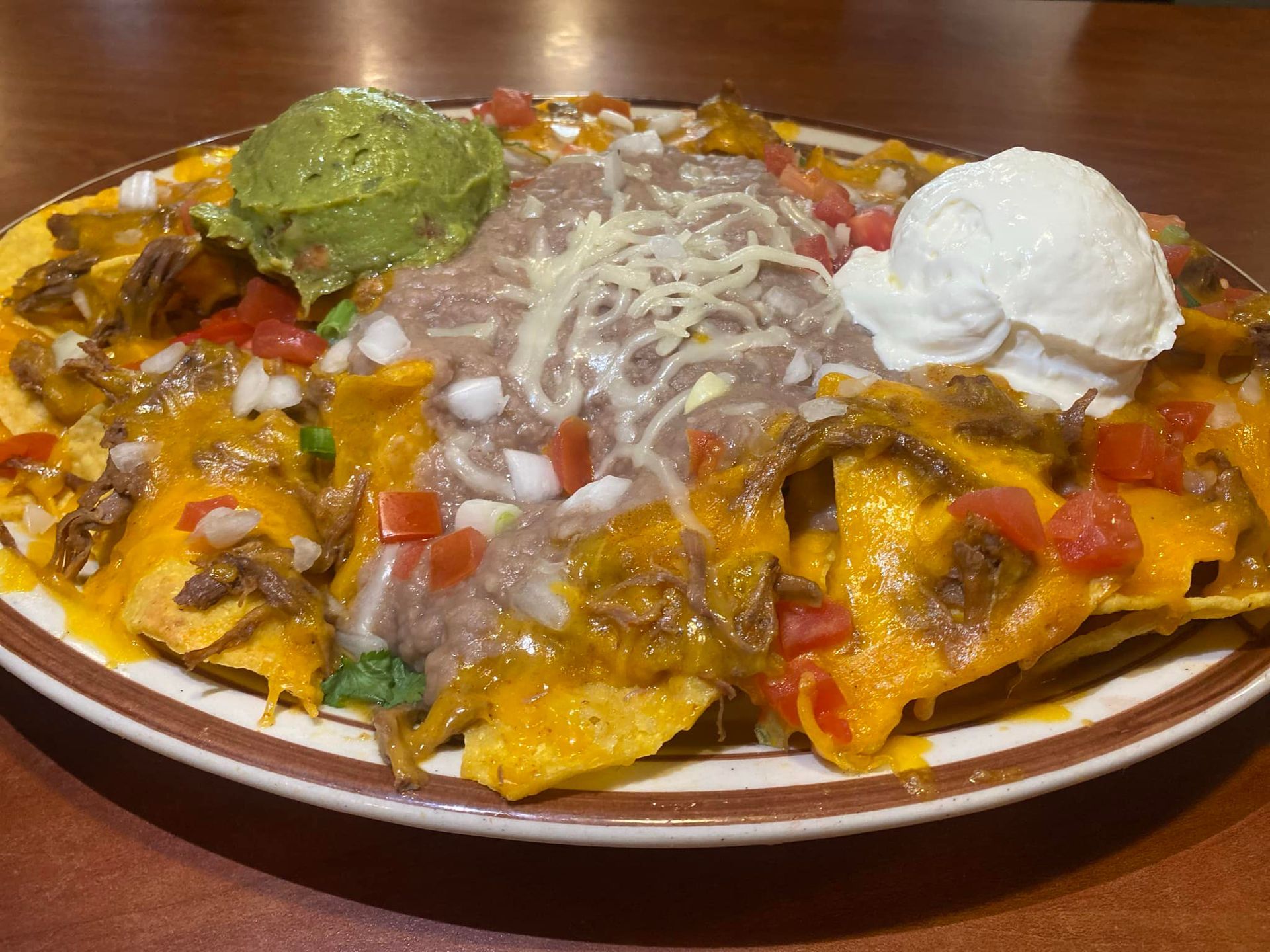 A plate of nachos with guacamole and sour cream on a table.