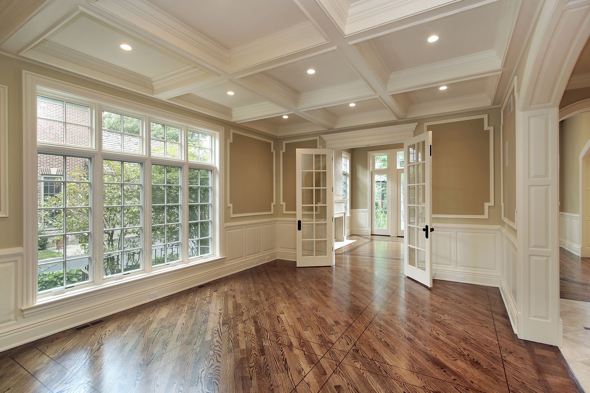 An empty living room with hardwood floors and lots of windows.