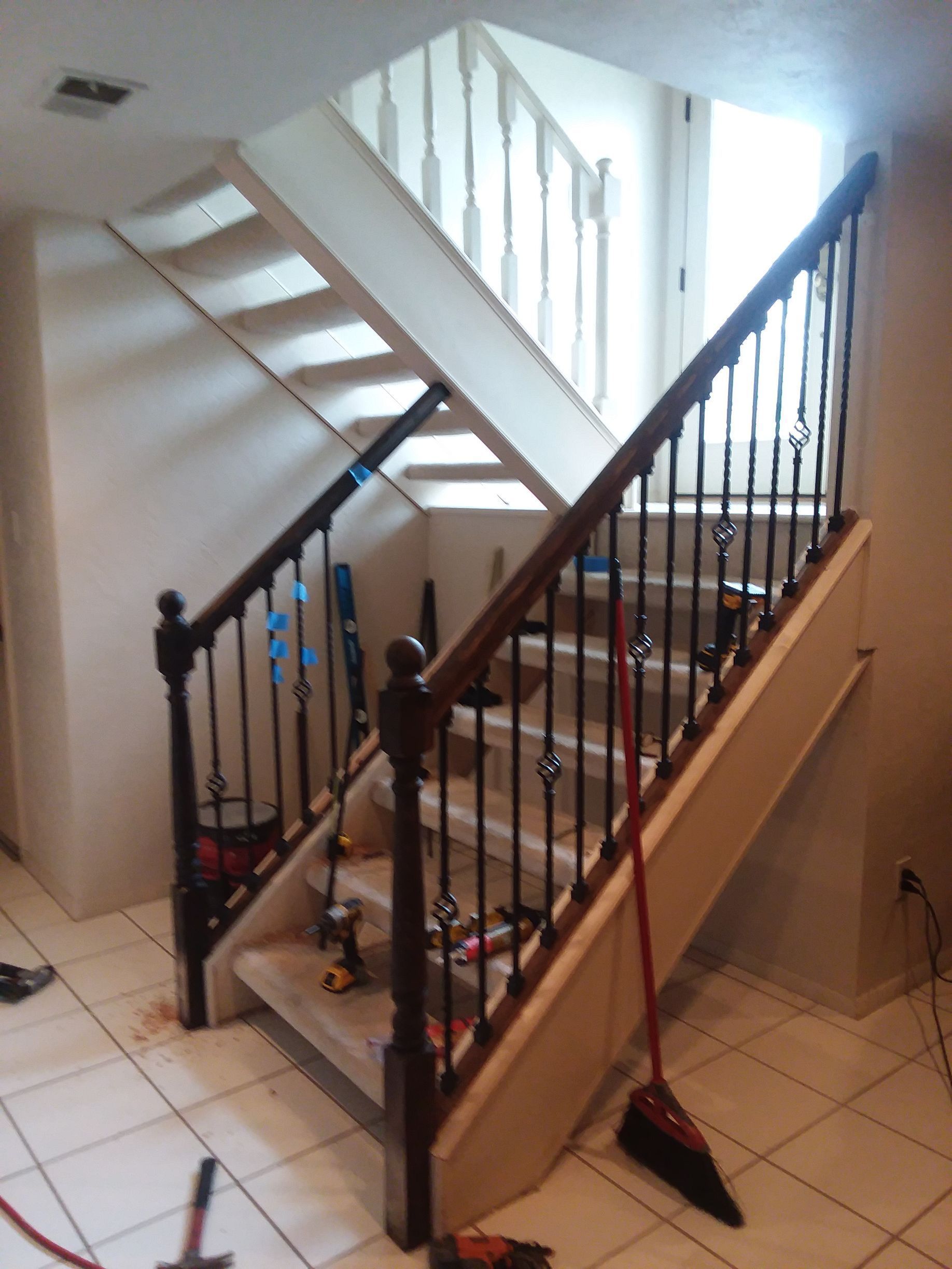 A staircase with a railing and a broom on the floor