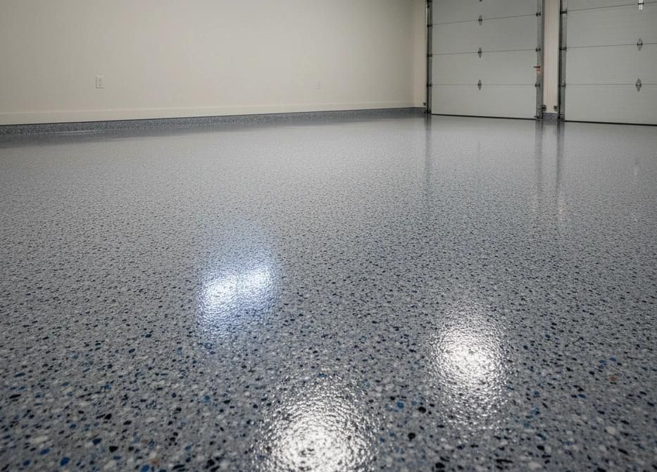 A polished, grey epoxy garage floor with blue and black speckles, reflecting overhead light.