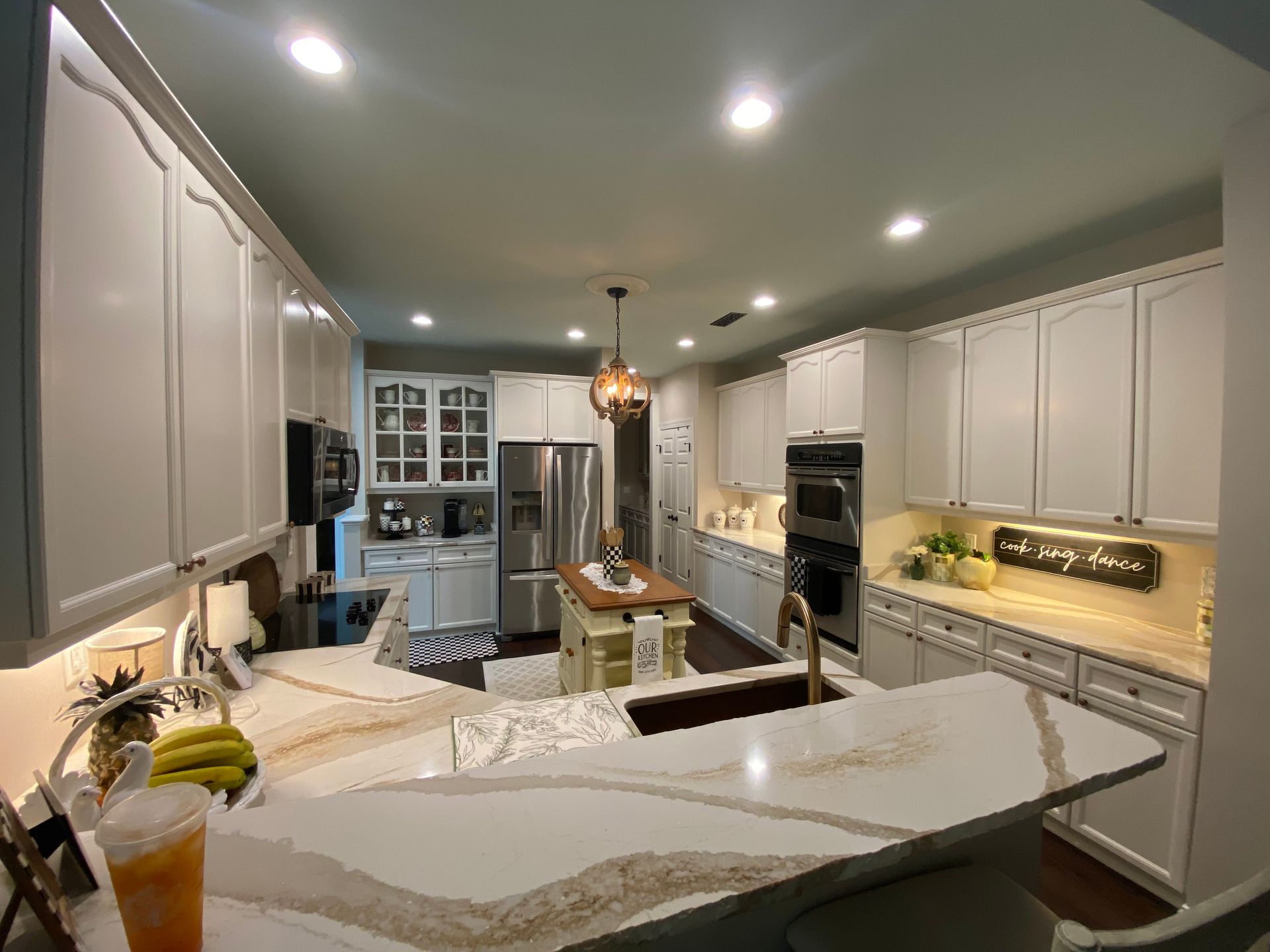 Narrow galley kitchen with gray cabinets, white countertops, and a stove on the left.