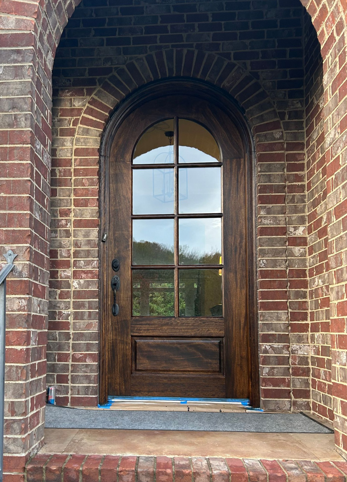Wooden double front door with frosted glass panels set in a red brick entryway