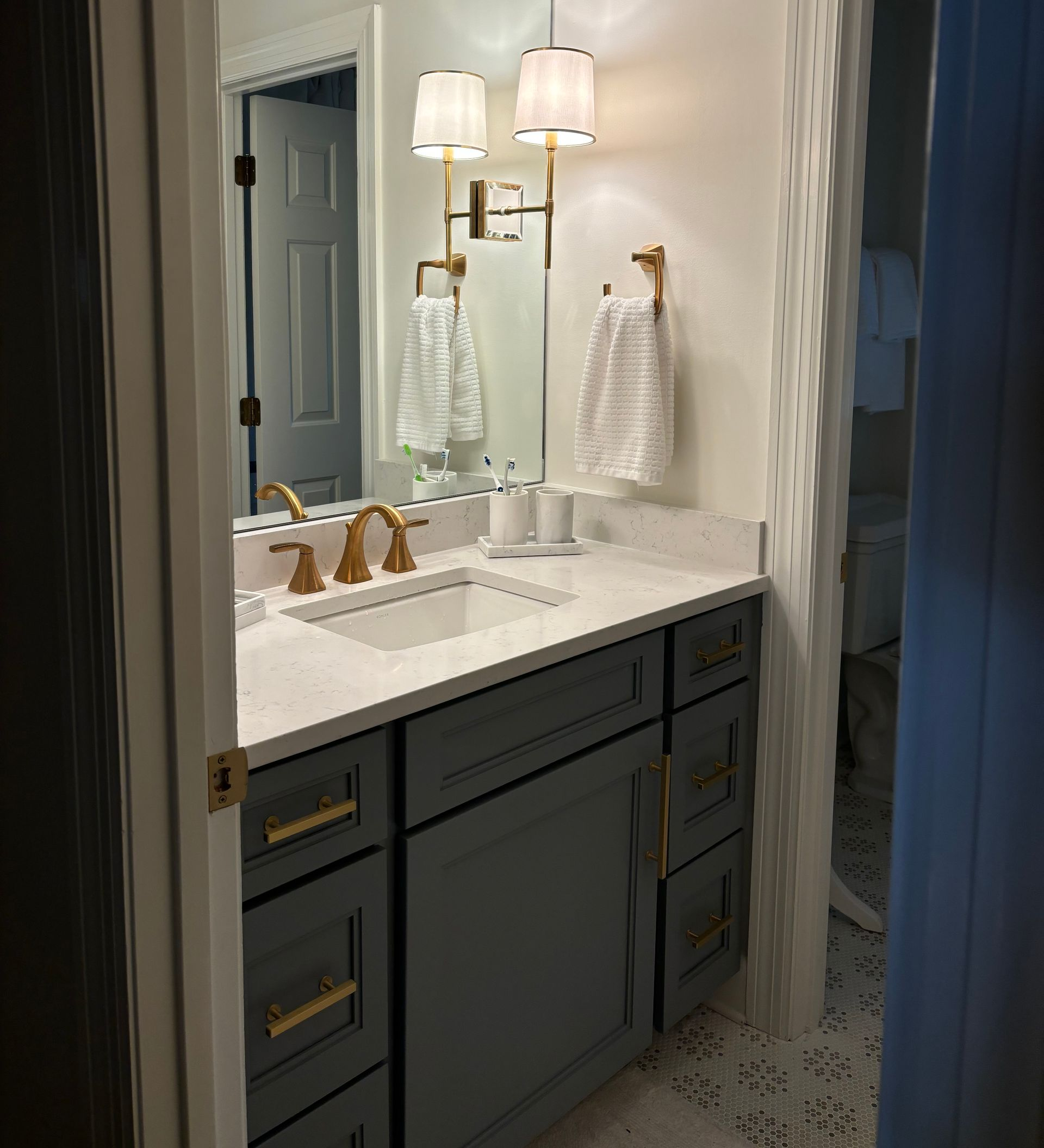 Double vanity bathroom with white cabinets, large mirrors, and gray walls in a bright, modern interior